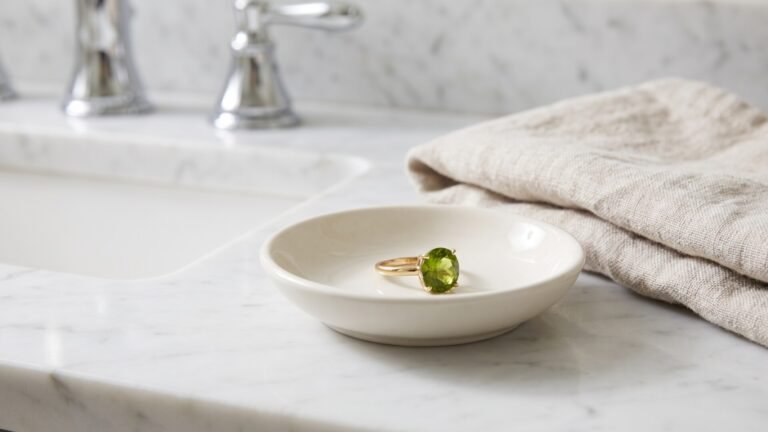 Peridot gemstone ring resting safely in a small ceramic dish beside a bathroom sink